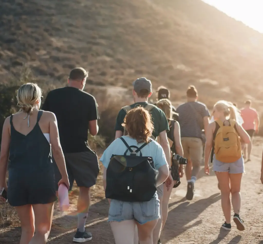 group walking a mountain trail at sunset